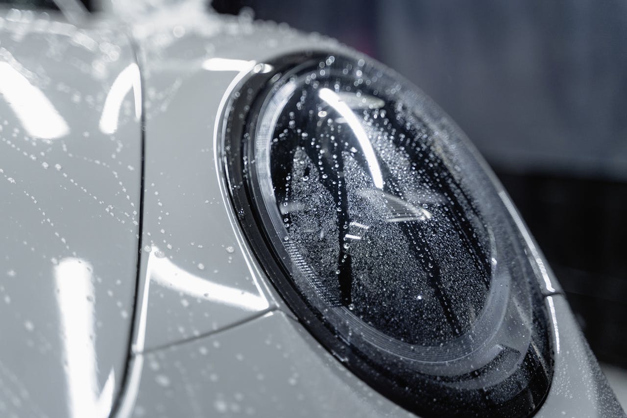 A detailed shot of a car headlight covered in water droplets, showcasing automotive design.